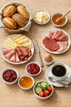 Fr&uuml;hst&uuml;ckstisch mit Br&ouml;tchen, K&auml;se, Wurst, Marmelade, Honig, Ei und Kaffee von oben