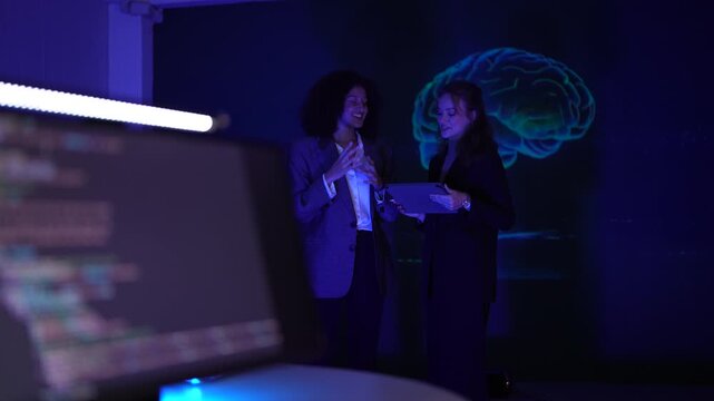 Female software engineers reviewing complex code. Developer team debugging predictive analytics syntax with AI brain visualization in neon workspace.
