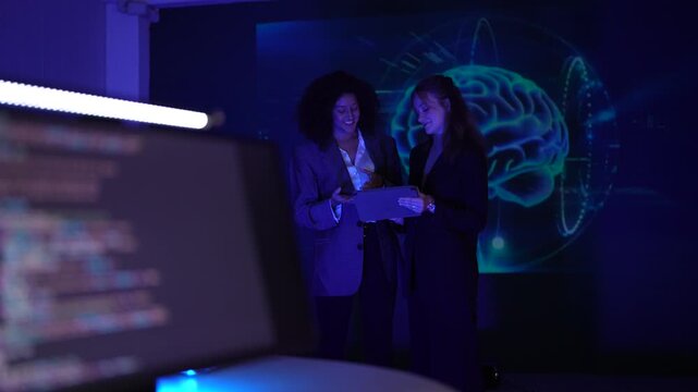 Diverse female data scientists collaborating on artificial intelligence algorithms. Computational neuroscientists discussing digital brain network via tablet.