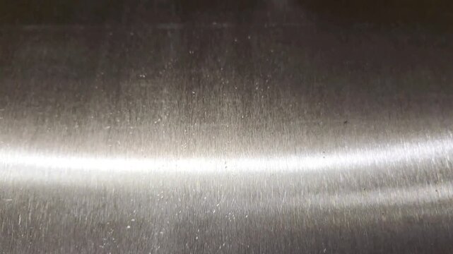 Brushed stainless steel metal texture background with sliding light reflections and polished surface
