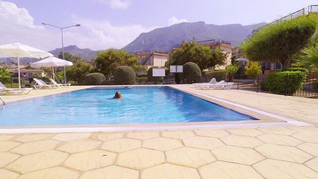 Overhead View of Woman Swimming in Blue Outdoor Pool at Private Villa Resort