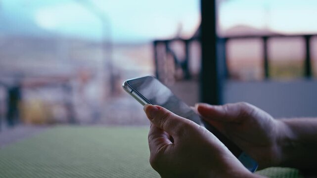 Woman Checking Messages on Phone While Sitting at Home Balcony with Mountain Scenery