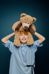 Joyful moments of a little boy playing with a fluffy teddy bear on a bright day