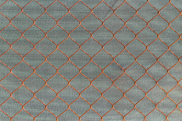 Zardzewiała siatka ogrodzeniowa na tle szarej ściany – metalowa kratownica, industrialna tekstura i zużyta powierzchnia. © Henryk Guziak