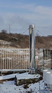 Metalowy komin zewnętrzny przy budynku, stalowa rura kominowa na zewnątrz, instalacja grzewcza i odprowadzanie spalin.