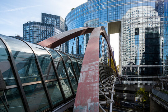 Modern abstract bridge walkway leading to glass skyscraper facade architecture in Paris La Defense business district with towers