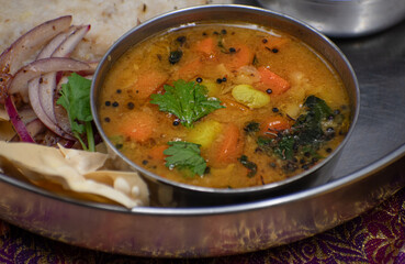 South Indian pongal, sambar, spinach curry and spice seasoned mango as thali meal. Vegan, plant based