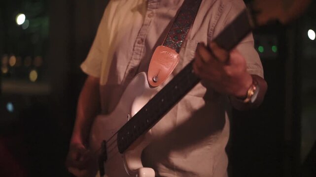 Close-up of bassist playing electric bass guitar while performance