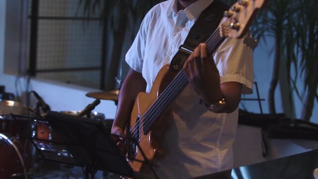 Close-up of bassist playing electric bass guitar while performance