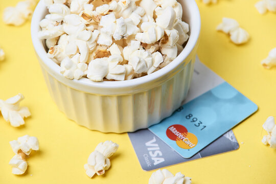 BARNAUL, SIBERIA, ALTAI REGION, RUSSIA - 18 February 2018: Popcorn in white bowl with credit cards on yellow background - snack and finance concept.