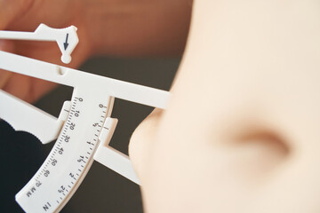Close-up of body fat caliper measuring young caucasian females skin for fitness assessment.