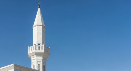 Obraz premium A majestic white minaret rises against a clear blue sky, symbolizing spirituality and architectural beauty