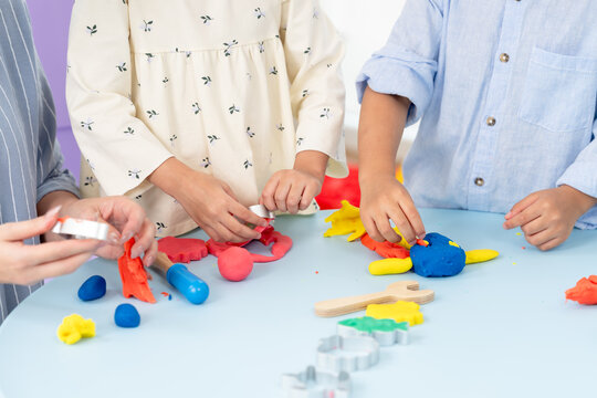 Asian single mom teaches sharing teamwork using playdough tools, toddlers roll cut bright shapes, child development cognitive skill practice, parent child interaction early education, indoor playroom.