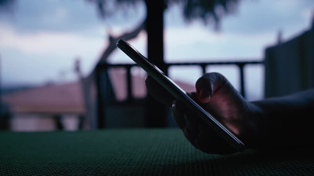 Close-Up of Female Using Smartphone on Terrace with Picturesque Mountain Landscape in Background