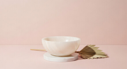 Minimalist bowl on white pedestal with decorative palm leaf  