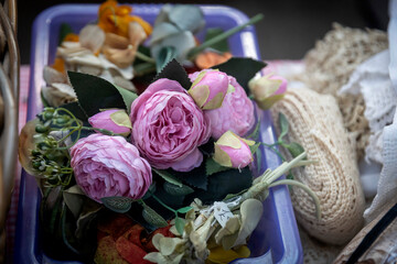 Faded artificial pink peonies and mixed flowers in purple plastic tray © elenarostunova