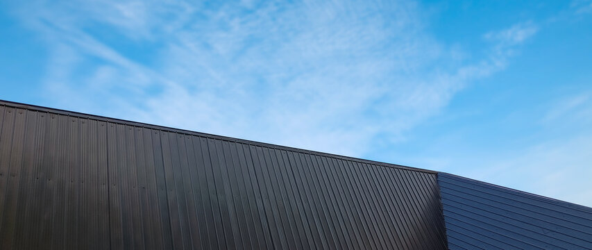 Metal sheet roof curve on blue sky. Modern construction, Metal ribbed arch span roof covering, Large building roof. not ai