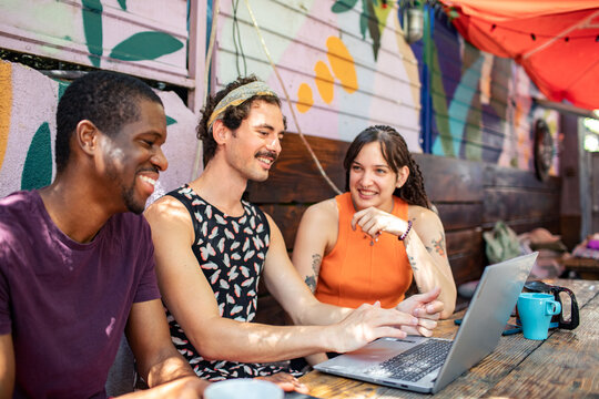 Young adults collaborating on laptop at outdoor cafe