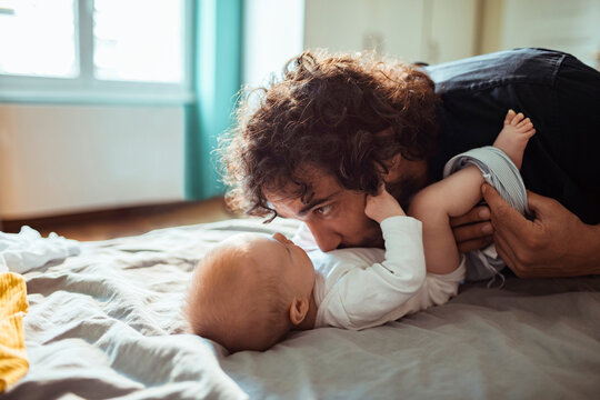Father kissing baby while playing on bed at home
