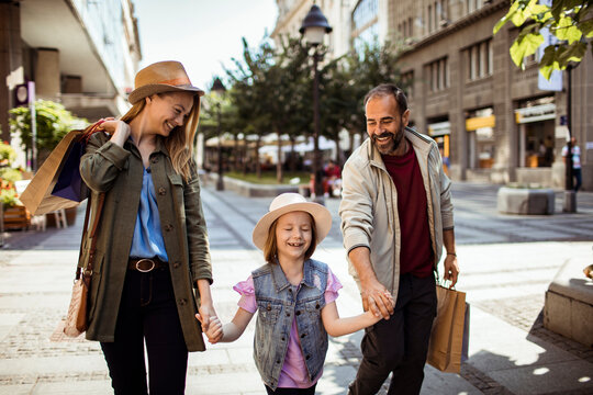 Parents and daughter walking on city shopping street