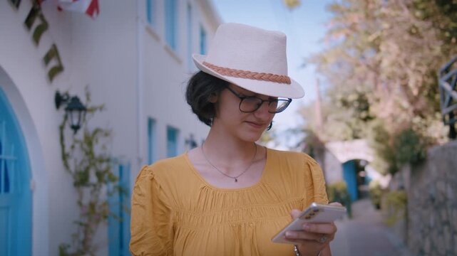 Traveler Woman in Wide-Brim Hat Browsing on Phone While Standing on Historic City Street