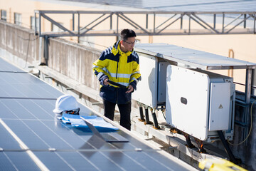 Solar power plant technician inspecting inverter equipment on rooftop with photovoltaic panels