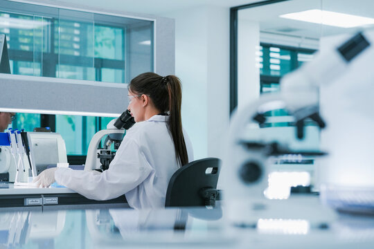 Cellular biologist analyzing morphological cell structures via high-resolution optical microscopy. Scientific researcher conducting biomedical experiment in modern laboratory facility.