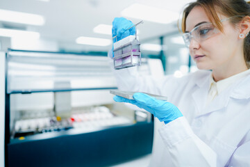 Fototapeta premium Pathological technician holding biopsy slide rack for quality inspection in clinical lab. Medical scientist preparing tissue sections for microscopic oncological diagnosis.