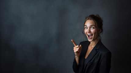Fototapeta premium confident businesswoman pointing up with excited expression in studio, happy stylish woman in black blazer showing cool gesture and bright smile, amazed professional woman with elegant makeup presenti