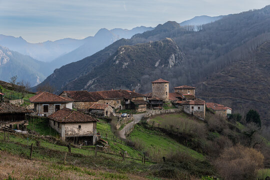 A scenic view of the ancient stone houses and traditional h&oacute;rreos (granaries) in the medieval village of Bandujo, surrounded by lush green mountains in the Proaza council, Asturias, Spain.