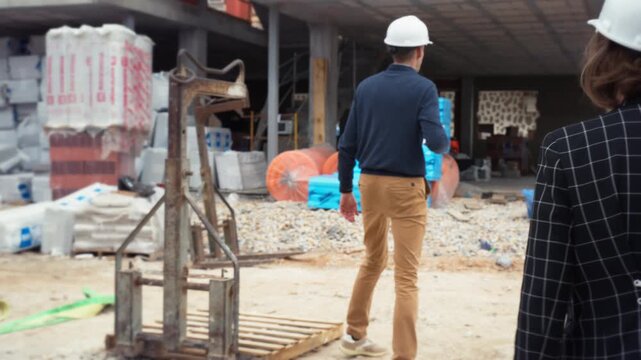 Architects reviewing structural design and technical details at construction site. Professional engineering team planning architectural solution for modern commercial building.
