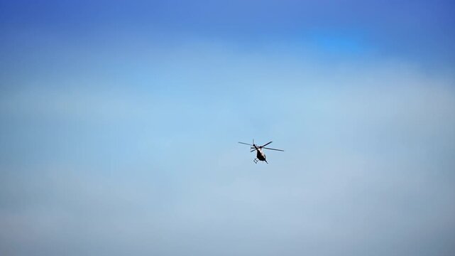 Blue sky with a helicopter flying. Rotorcraft from low angle view.