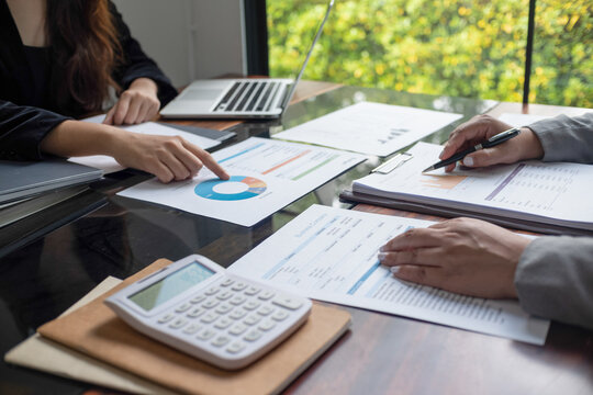 Cropped image of professional businesswoman, entrepreneur or accountant working on a financial report paperwork at her desk, using calculator or laptop
