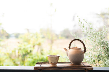 Earthenware tea pot and tea cup arranged on wooden tray