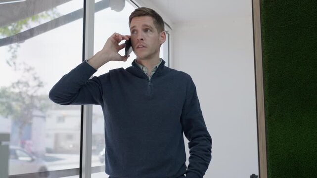 Confident business executive speaking on smartphone in modern office. Corporate negotiation call focused on strategic decision making, partnership development and commercial growth.