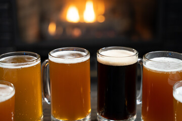 Assorted beer mugs on table with fireplace background