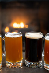 Assorted beer mugs on table with fireplace background