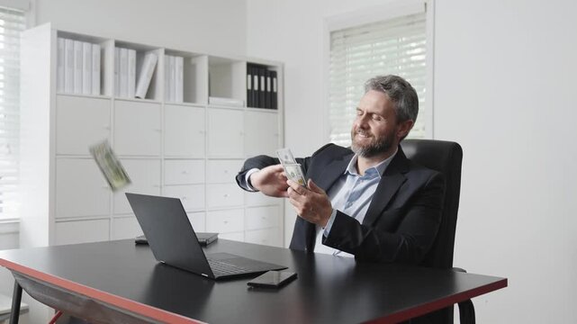 Flying cash and money rain in business office. Businessman throws money during corporate celebration. Slow motion money falling around man in suit. Office success moment with man throwing cash.