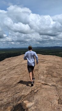 Arabic guy exploring the ancient lion rock landmark in Sri Lanka, watching the distant horizon from the top of the giant stone cliff in a famous UNESCO heritage destination in Asia