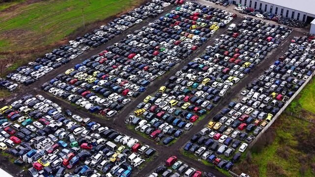 Panoramic high angle view massive collection of end-of-life vehicles in a rural industrial area of Bulgaria. Wide aerial perspective of an extensive vehicle salvage yard.