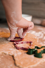 Happy boy making gingerbread cookies with hands using a cookie cutter. Close up
