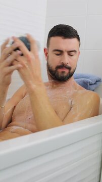 Man Using Mesh Pouf Loofah in the Bathtub 