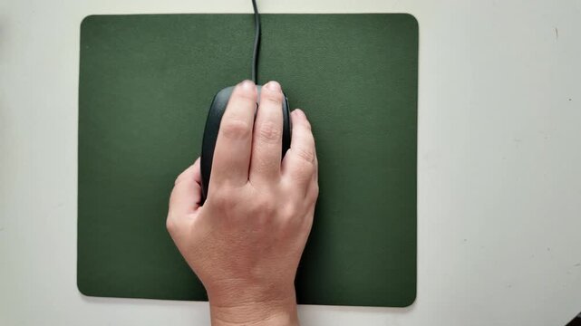 Woman using a mouse on a mouse pad and desk, detail of a modern working environment, top view