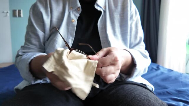 A woman wipes her glasses with a cloth so as not to damage the lenses.