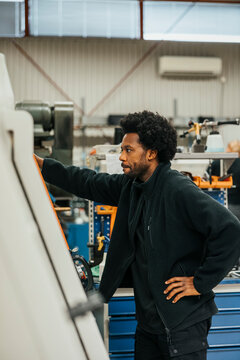 Male factory worker working on machine during manufacturing process