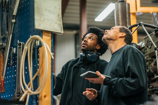 Low angle view of male workers operating machine in manufacturing industry