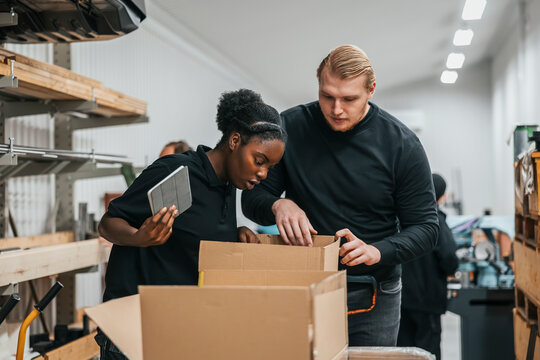 Female and male warehouse workers packing cardboard boxes for shipment
