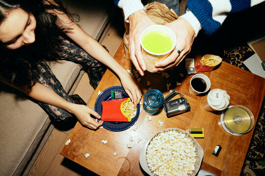 High angle view of man and woman enjoying fast food and drinks at home