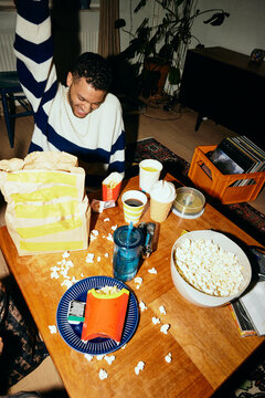 Cheerful man with fast food spread on table at home