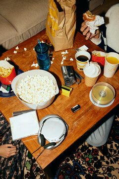 High angle view of friends eating unhealthy snacks sitting around table at home